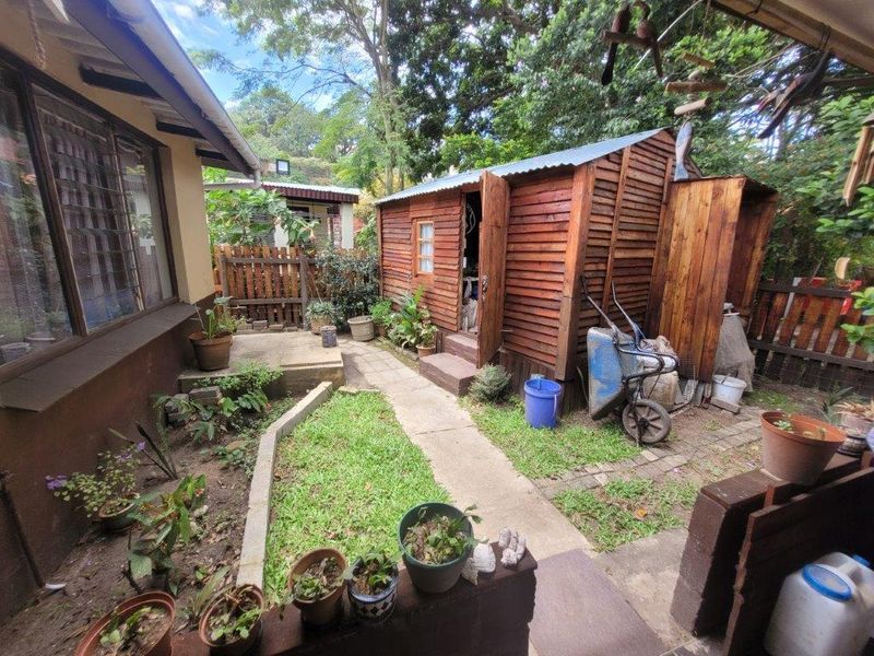 Rear garden area featuring a timber storage shed, paved pathways, and established boundary fencing, offering potential for landscaping and outdoor utility space.