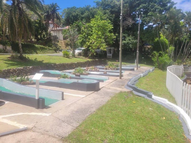 Outdoor miniature golf course facility featuring paved walkways, retaining walls, and established garden landscaping within the townhouse complex grounds.