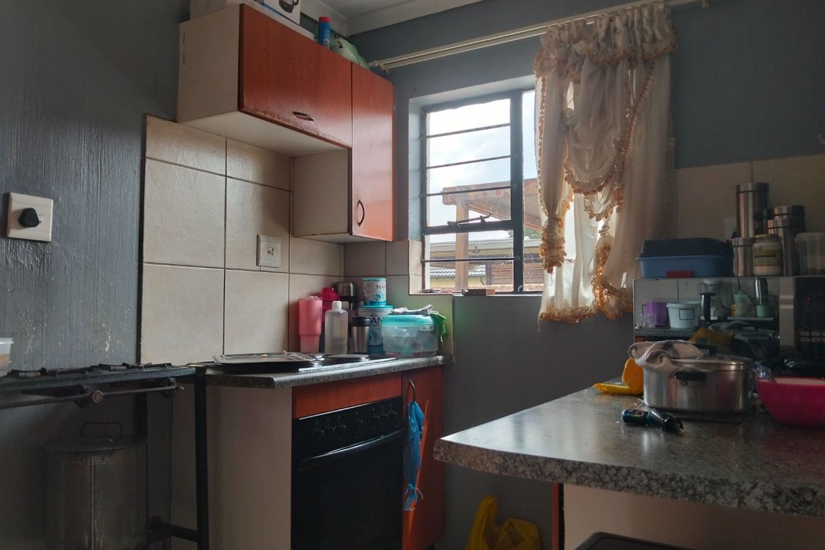 Compact kitchen featuring built-in oven, hob, tiled splashback, and laminate countertops, requiring cosmetic updates to modernize the space.