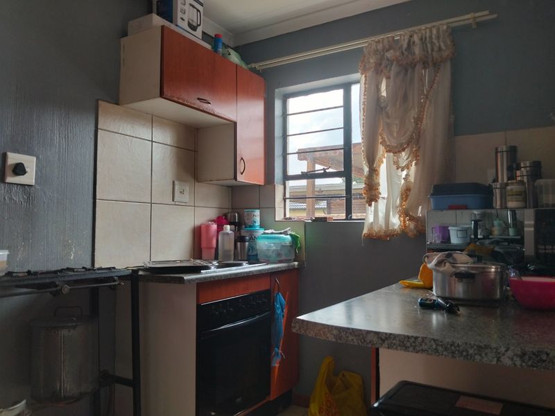 Compact kitchen featuring built-in oven, hob, tiled splashback, and laminate countertops, requiring cosmetic updates to modernize the space.