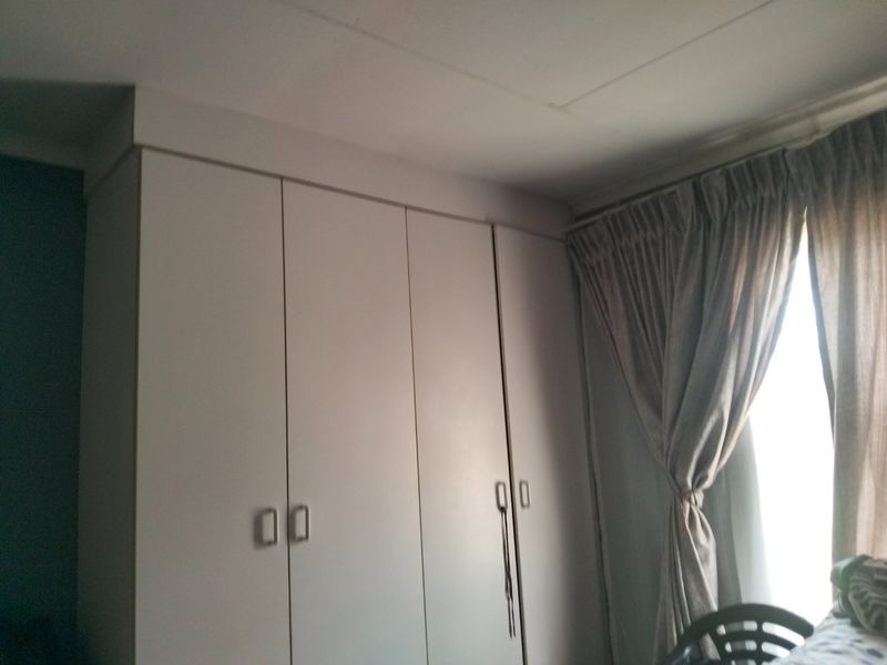 Bedroom featuring floor-to-ceiling built-in cupboards and window treatments.