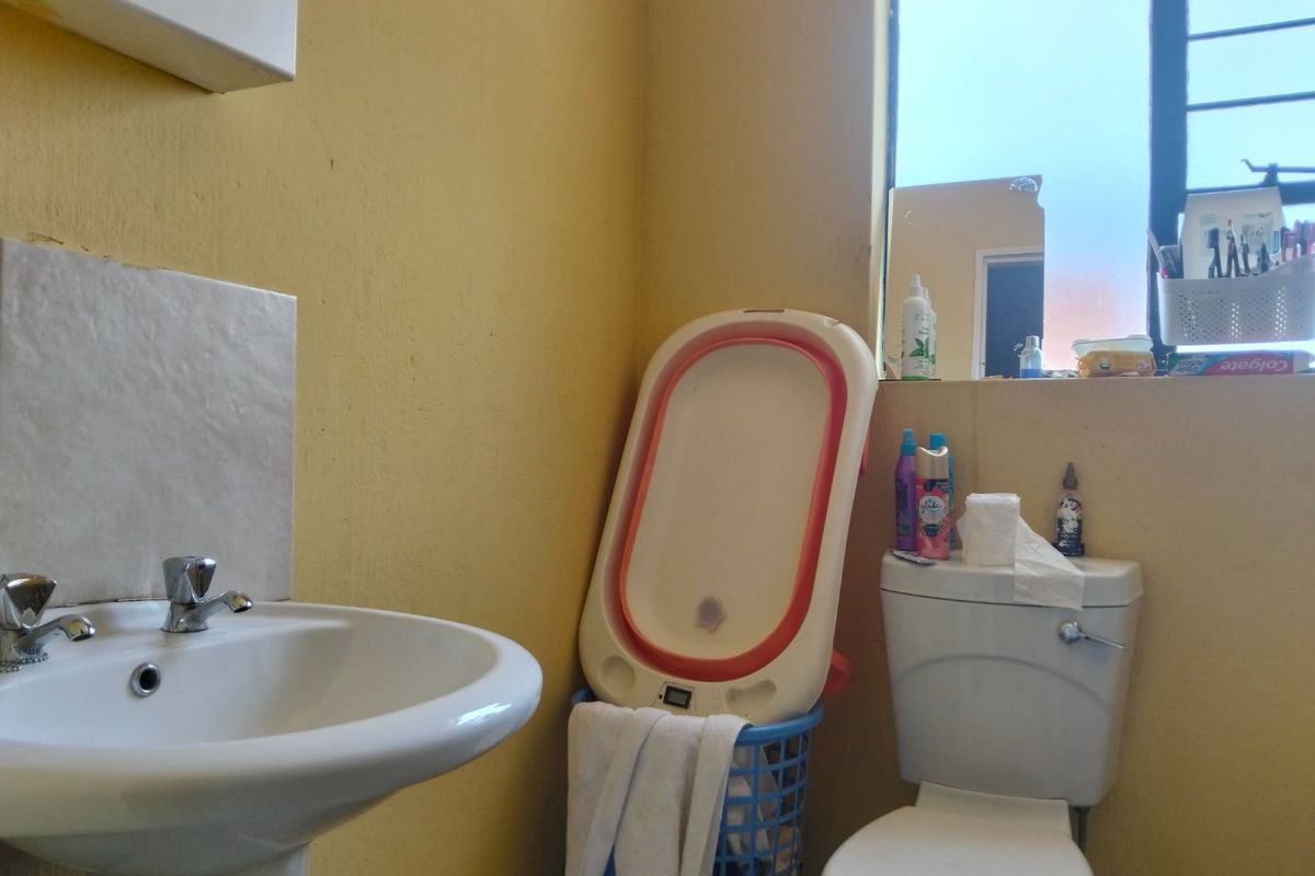 A functional bathroom featuring a pedestal basin and standard toilet, requiring cosmetic updates to the wall finishes.