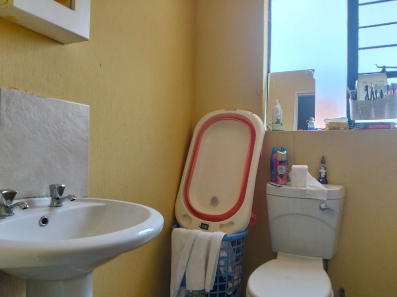 A functional bathroom featuring a pedestal basin and standard toilet, requiring cosmetic updates to the wall finishes.