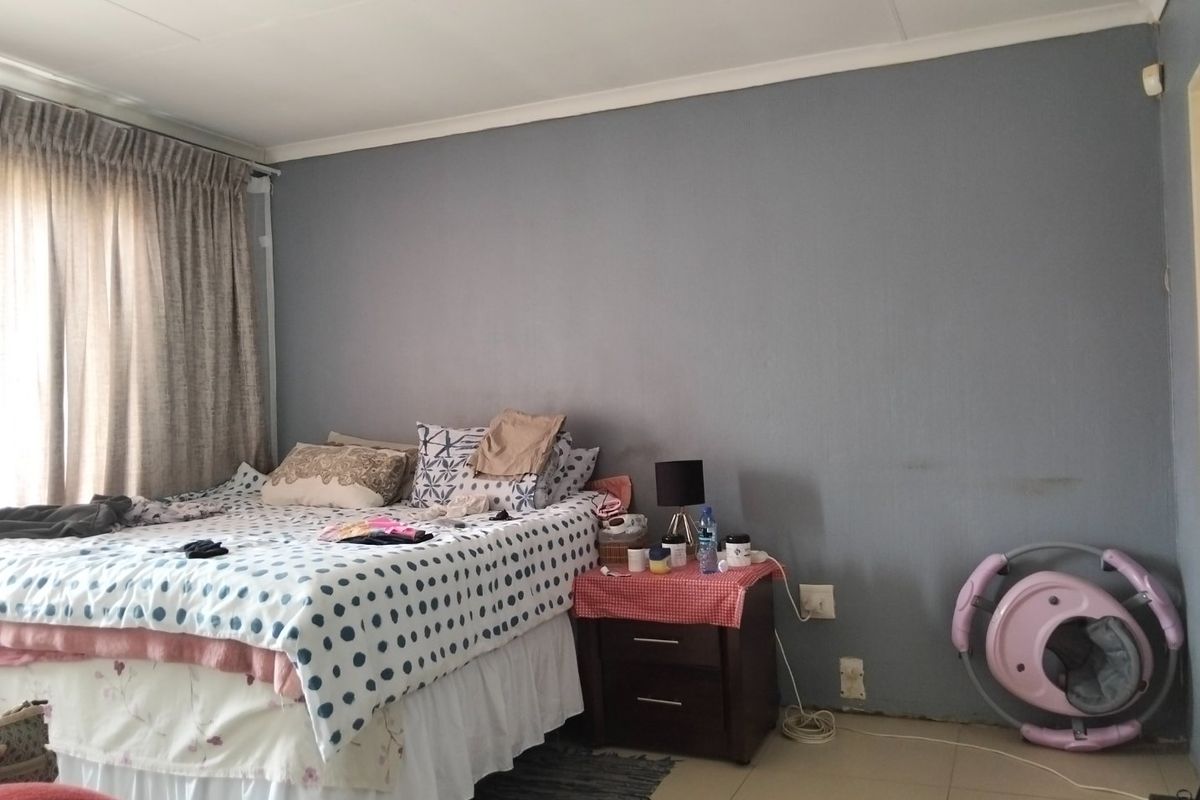 A bedroom featuring tiled flooring and neutral grey walls, currently requiring minor cosmetic repairs such as skirting board installation and wall touch-ups.