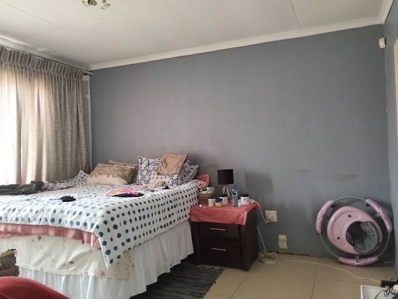 A bedroom featuring tiled flooring and neutral grey walls, currently requiring minor cosmetic repairs such as skirting board installation and wall touch-ups.