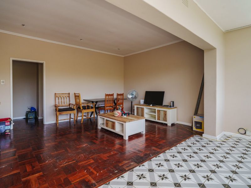 Open plan living area featuring a combination of classic parquet flooring and decorative patterned tiles, offering a versatile space for lounge and dining arrangements.