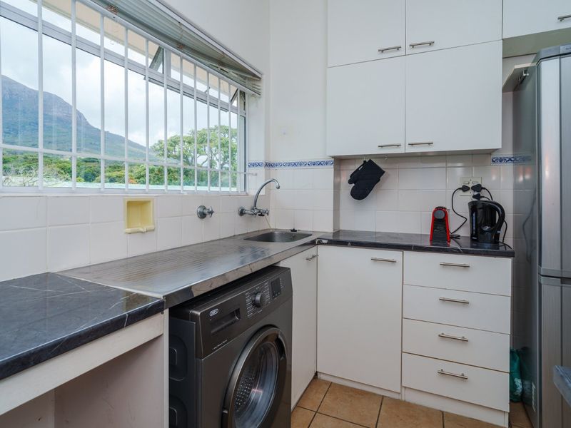 Compact kitchen featuring white cabinetry, dark laminate countertops, tiled backsplash, and a window with mountain views.