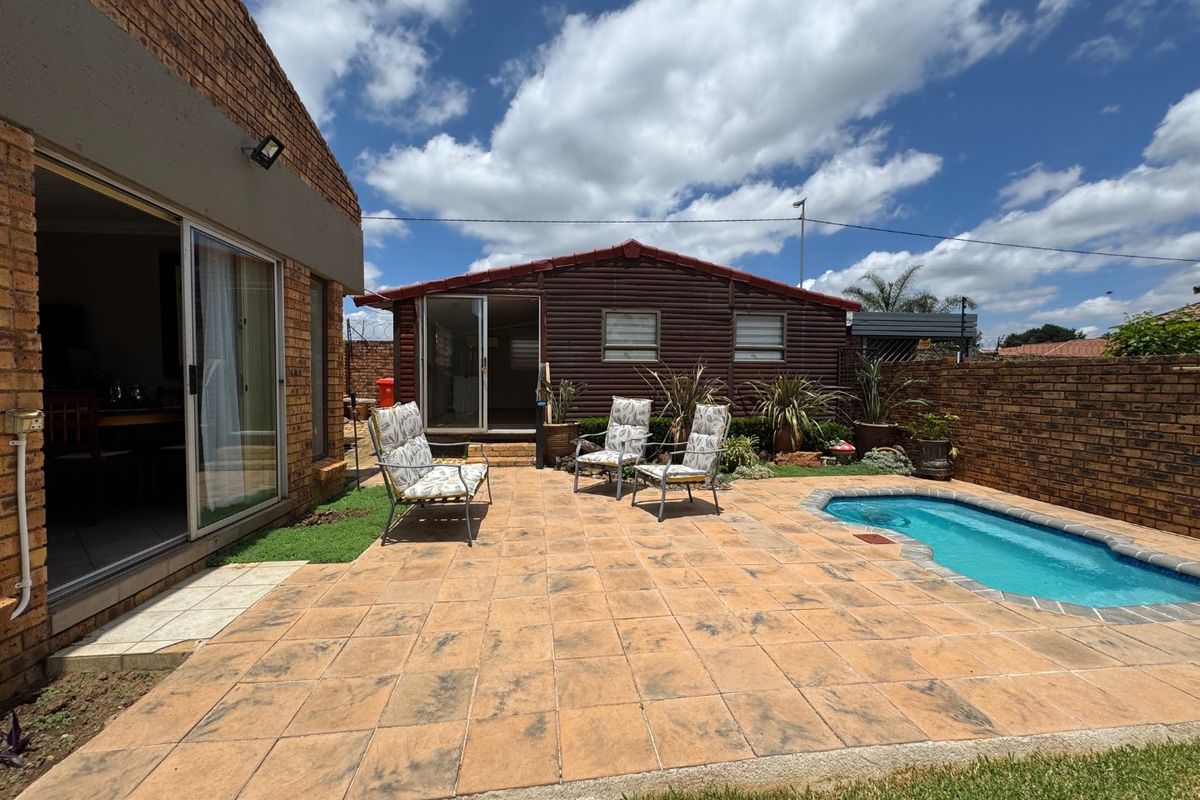 Rear exterior view featuring a paved patio area, a small swimming pool, and access to the main dwelling and a secondary structure.