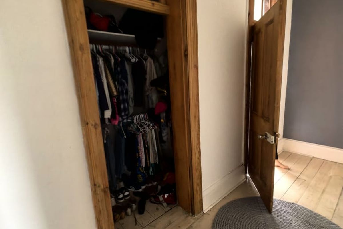 Bedroom featuring original timber flooring, classic timber door frames, and a built-in closet with overhead storage.