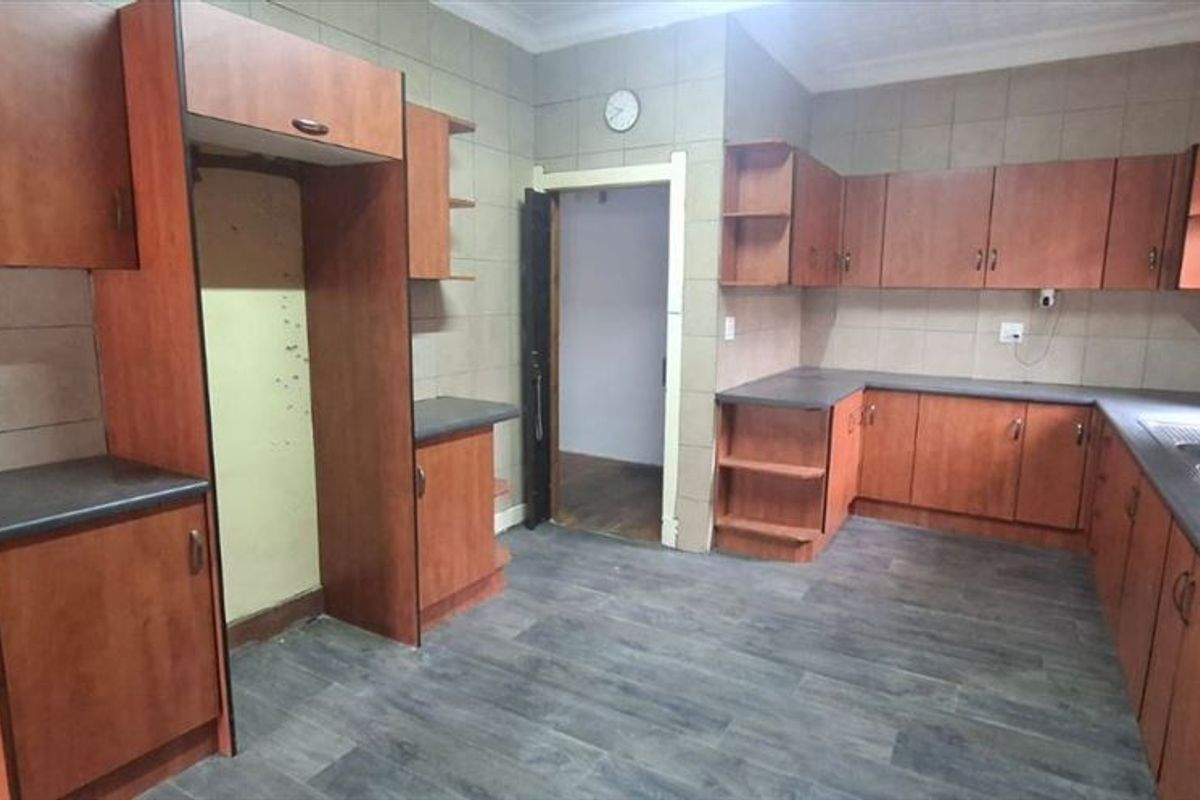 A functional kitchen featuring laminate cabinetry, dark countertops, a double basin sink, and built-in cooking appliances with tiled splashbacks.