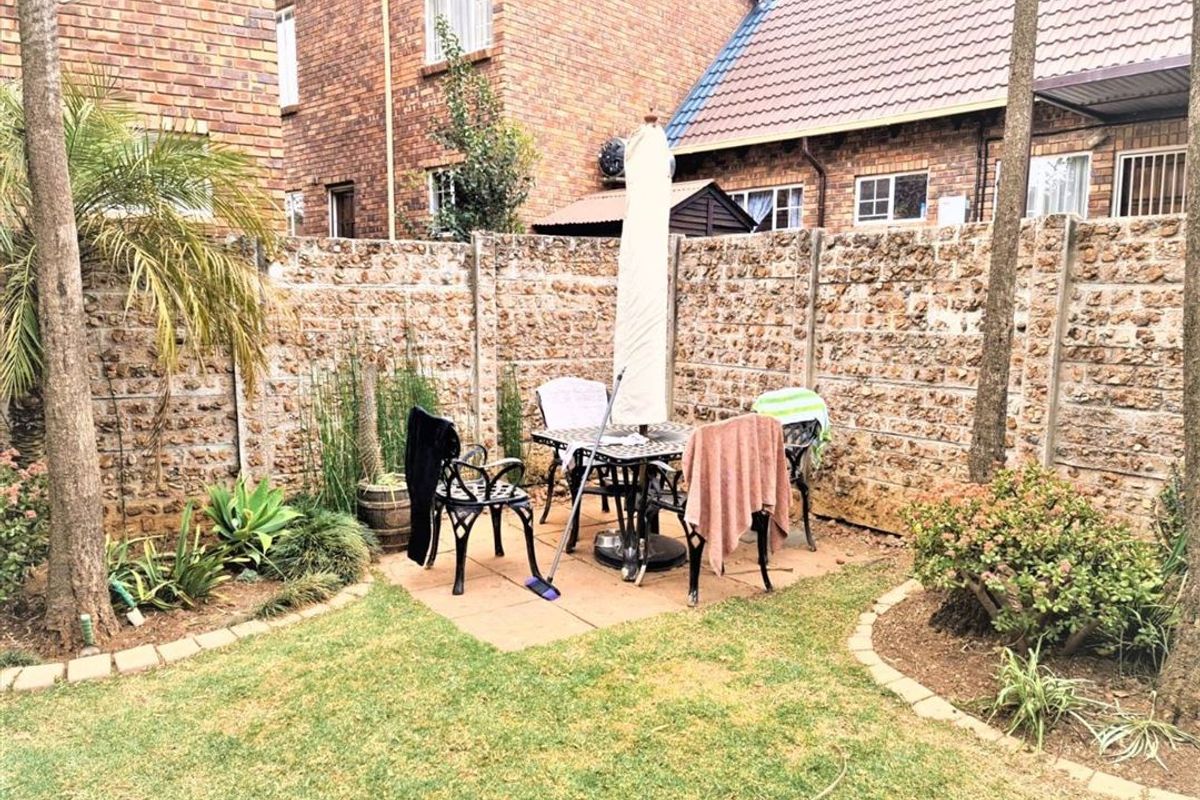 A private rear garden featuring a paved patio area, established landscaping, and a precast concrete boundary wall.