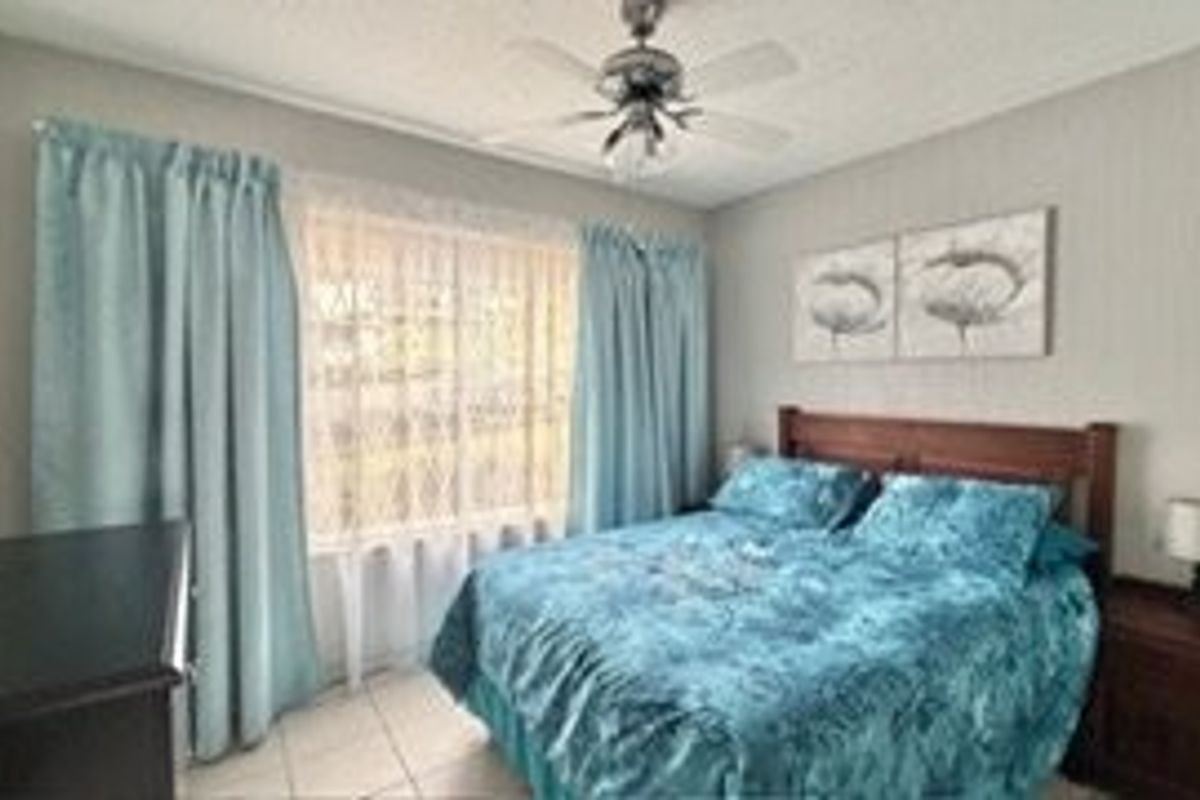 A bedroom featuring tiled flooring and a ceiling fan, providing a functional and comfortable living space.