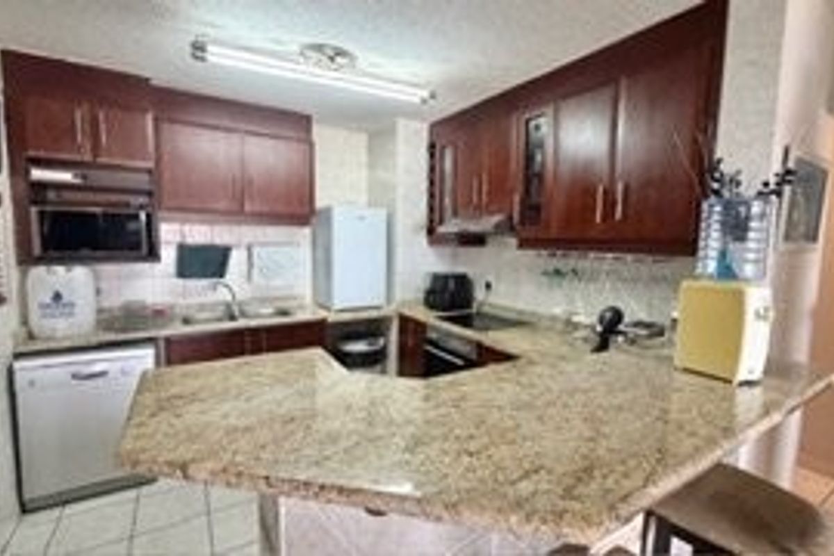 A functional kitchen featuring dark wood cabinetry, granite countertops, a breakfast bar, and integrated appliances, offering a practical layout for daily use.