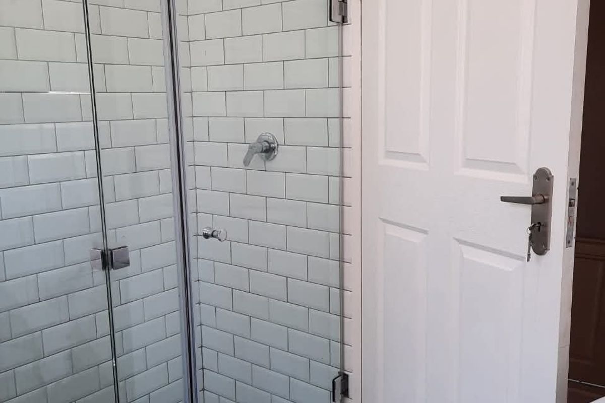A modern bathroom featuring a glass-enclosed shower with white subway tile walls and decorative patterned floor tiles.
