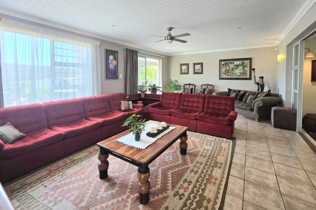 Spacious living room featuring tiled flooring, a tongue and groove ceiling with a fan, and large windows providing ample natural light.