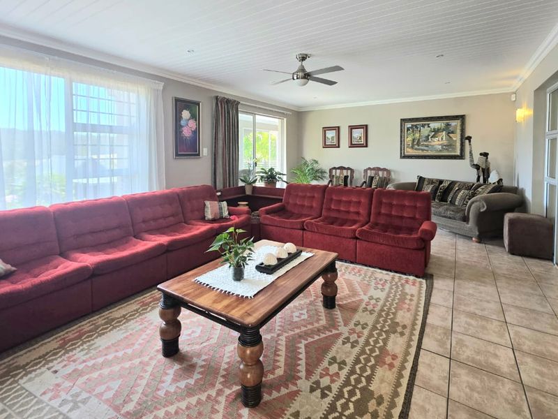 Spacious living room featuring tiled flooring, a tongue and groove ceiling with a fan, and large windows providing ample natural light.