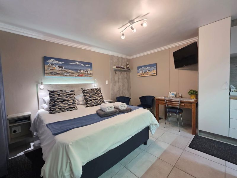 A well-maintained bedroom featuring tiled flooring, built-in wardrobe storage, and modern ceiling spotlighting, providing a comfortable and functional living space.