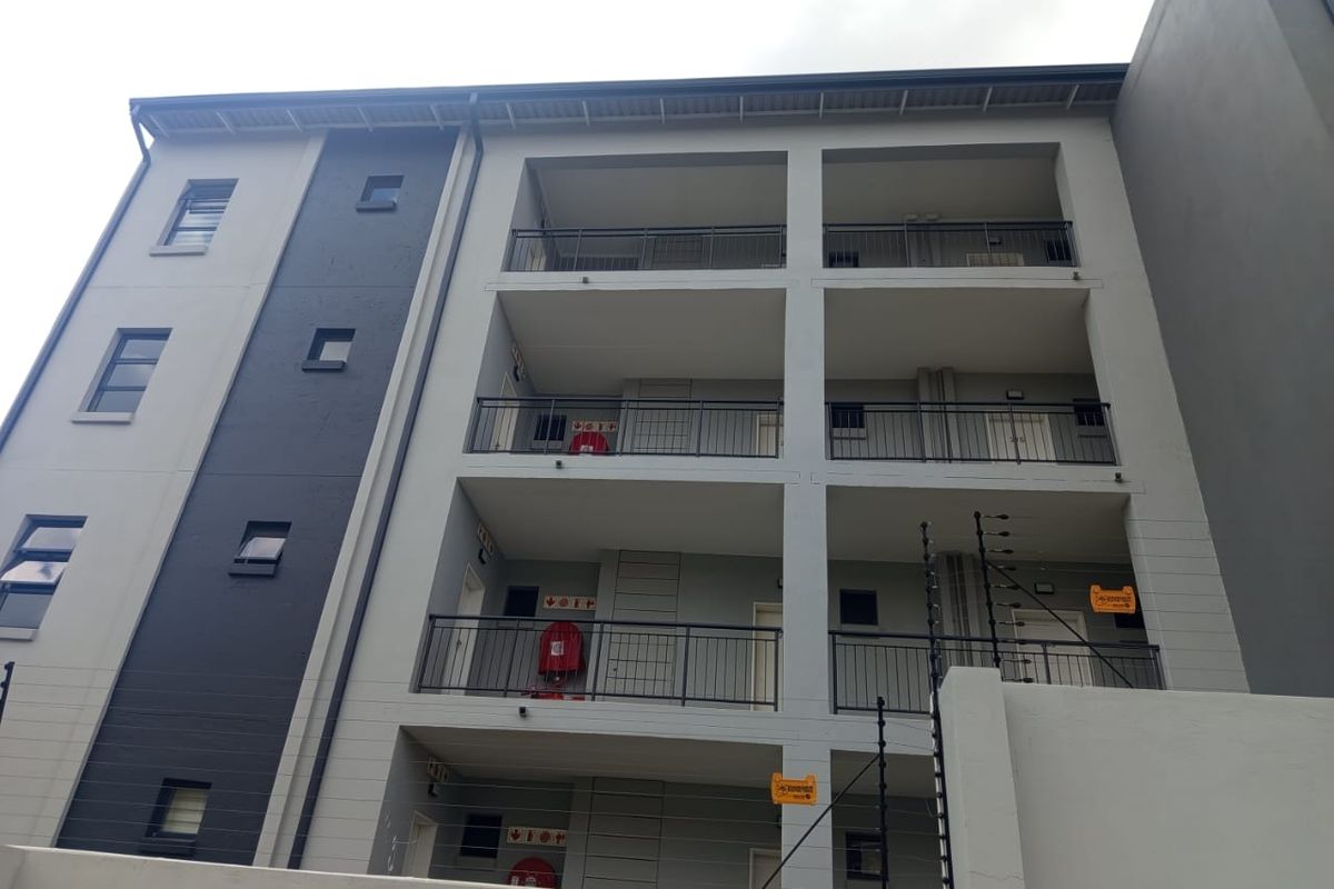 A view of the apartment building exterior featuring multiple levels of balconies with metal railings and integrated security features.