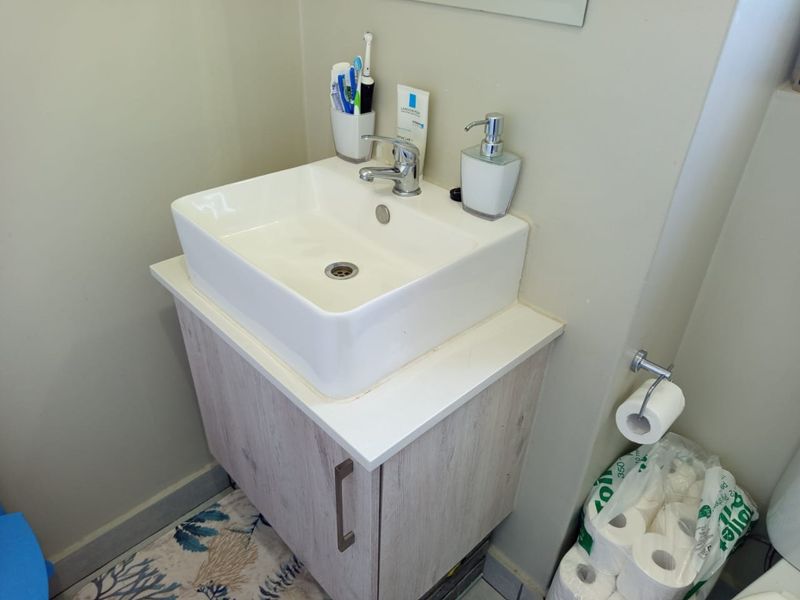 A compact bathroom featuring a modern vessel sink mounted on a light wood-finish vanity cabinet with chrome hardware.