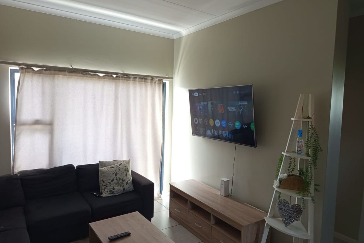 A living room featuring tiled flooring, coving, and a wall-mounted television, providing a functional and comfortable space.