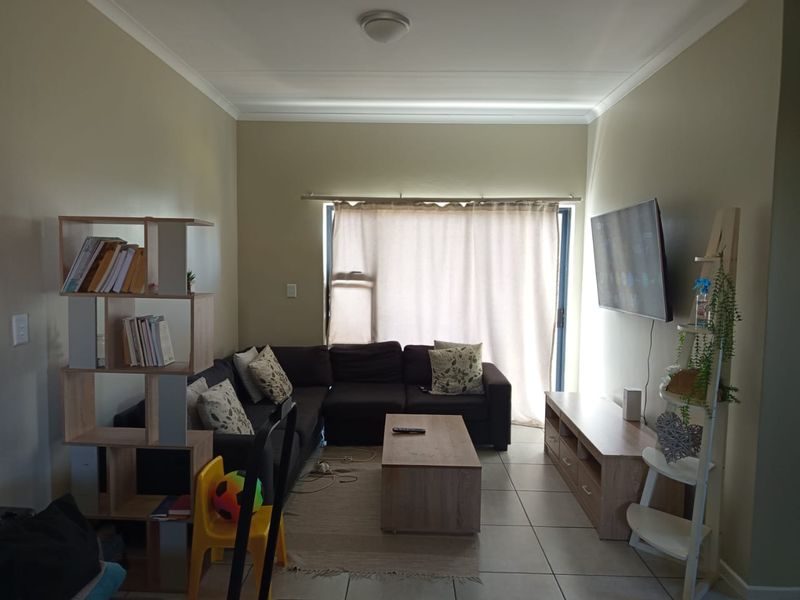 A functional living room featuring tiled flooring and a sliding glass door that provides natural light, offering a comfortable space for relaxation.