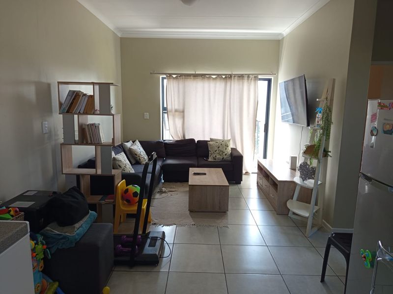 Open-plan living area featuring neutral tiled flooring and a sliding glass door providing access to the exterior.