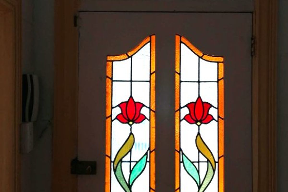 A classic entrance door featuring decorative stained glass panels and a matching transom window, providing character and natural light to the entry area.