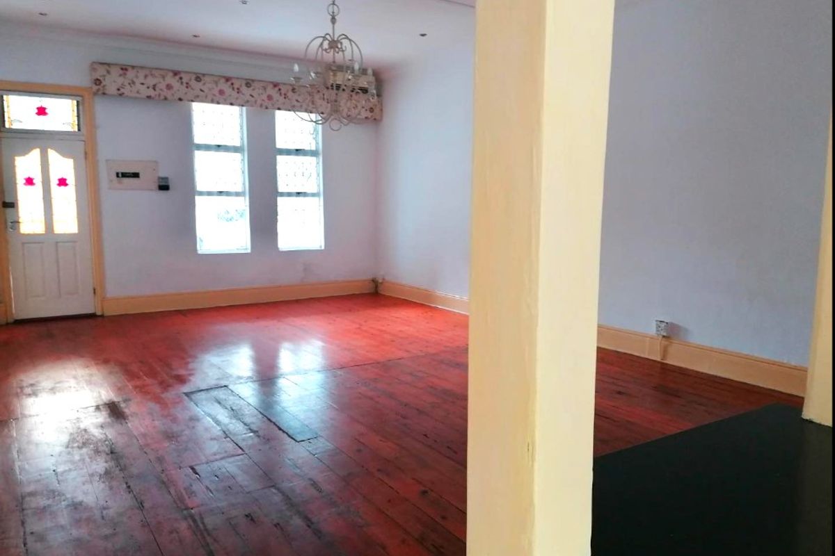 An empty living room featuring polished timber flooring, a structural column, and natural light through multi-pane windows.