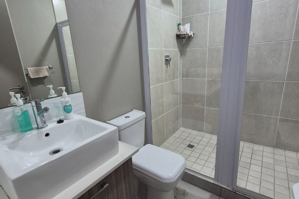 Modern bathroom featuring a glass-enclosed walk-in shower, a contemporary vanity with a basin, and neutral floor-to-ceiling tiling.