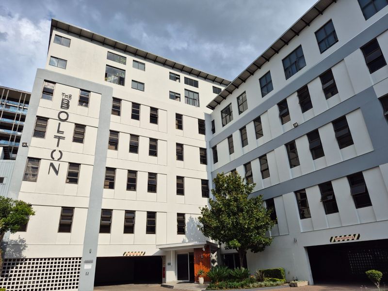 Exterior view of The Bolton apartment building, showcasing its modern multi-story facade, architectural design, and ground-level parking access.