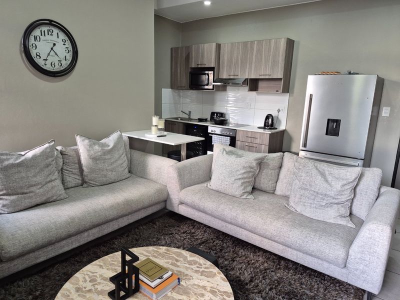 Open-plan living area featuring a modern kitchen with wood-grain cabinetry, integrated appliances, and a comfortable lounge space.