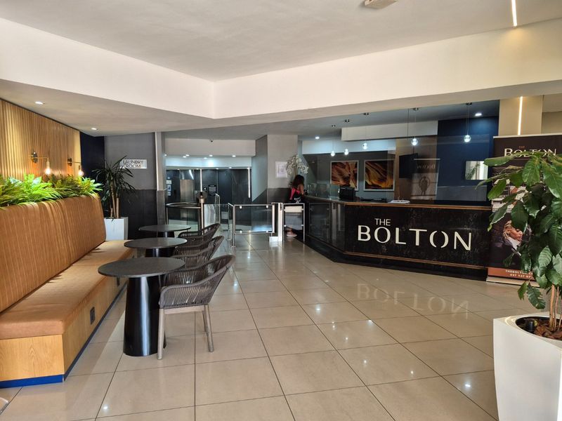 Modern apartment building lobby featuring a reception desk, tiled flooring, and integrated seating area with contemporary finishes.