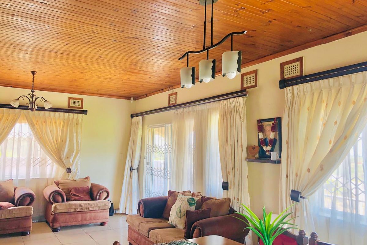 Spacious living area featuring a warm timber tongue and groove ceiling, tiled flooring, and large windows providing ample natural light.