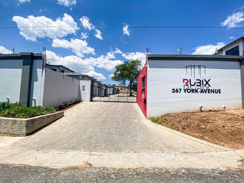 Front entrance view of Rubix complex at 267 York Avenue, featuring a paved driveway, secure gate access, and perimeter boundary walls with electric fencing.
