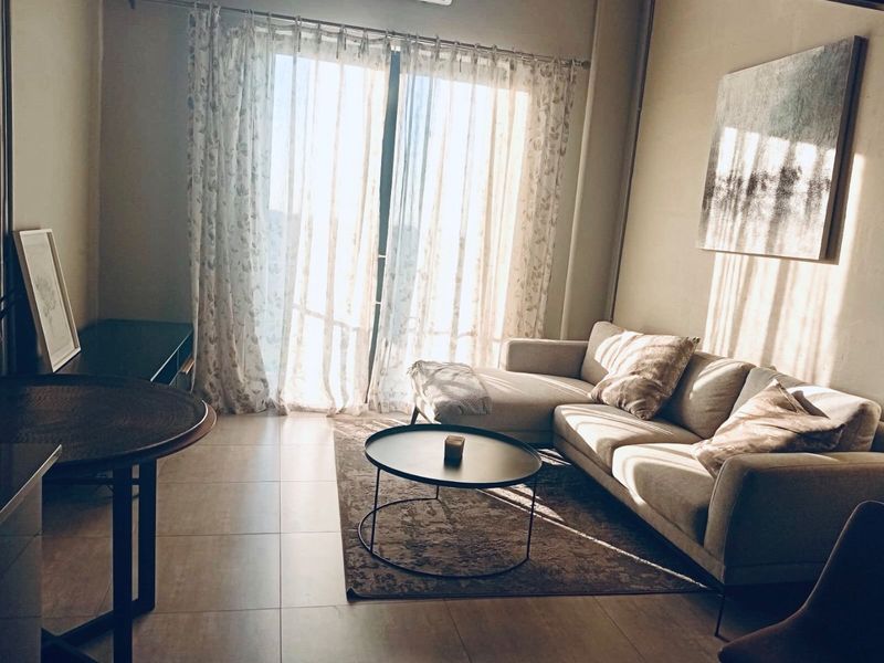 A bright living room featuring tiled flooring and a large sliding glass door that provides natural light and access to the exterior.