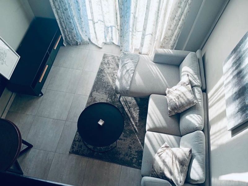A bright living room area featuring neutral tiled flooring and access to a balcony through large sliding glass doors.
