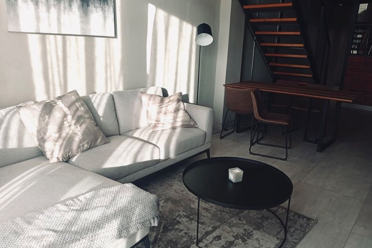A modern living area featuring tiled flooring and an open-tread staircase, creating a bright and contemporary open-plan atmosphere.