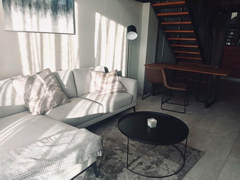 A modern living area featuring tiled flooring and an open-tread staircase, creating a bright and contemporary open-plan atmosphere.