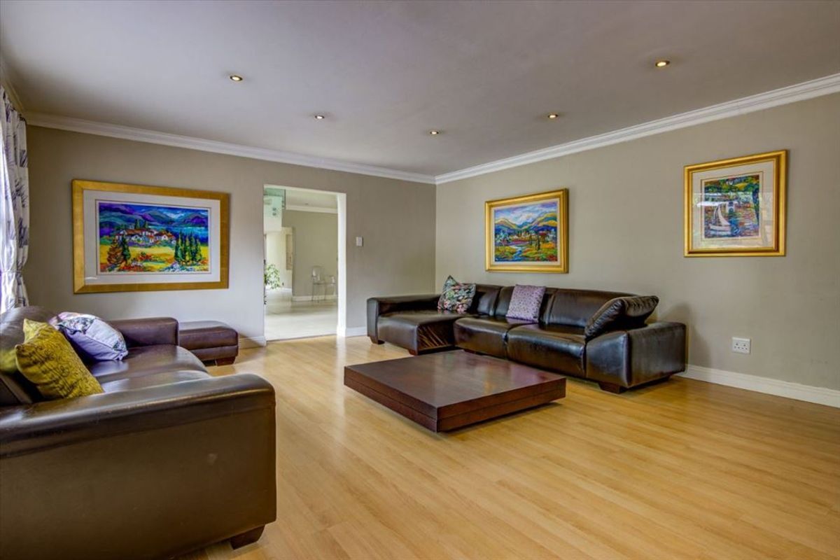 Spacious living room featuring light wood laminate flooring, recessed ceiling lighting, and crown molding, providing a comfortable and well-maintained area for relaxation.