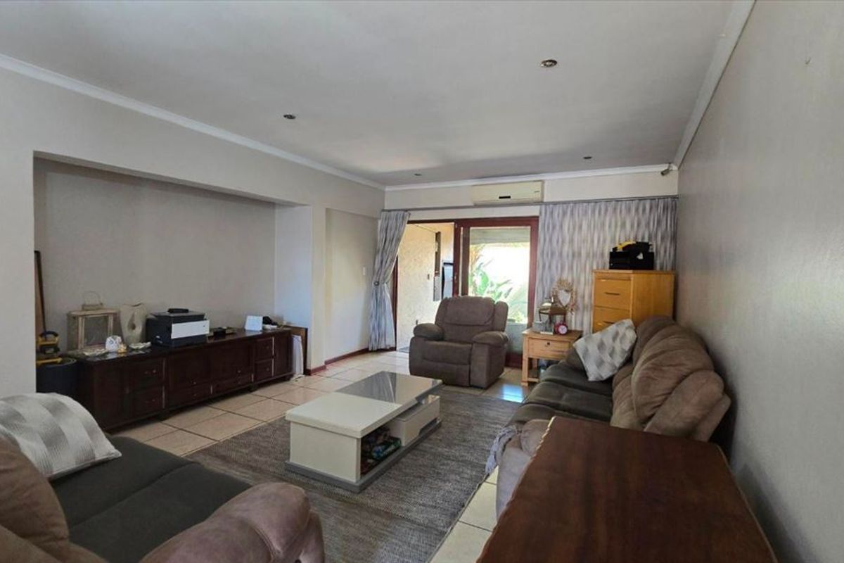 Spacious living room featuring tiled flooring, recessed lighting, a wall-mounted air conditioner, and direct access to the outdoor area through sliding glass doors.