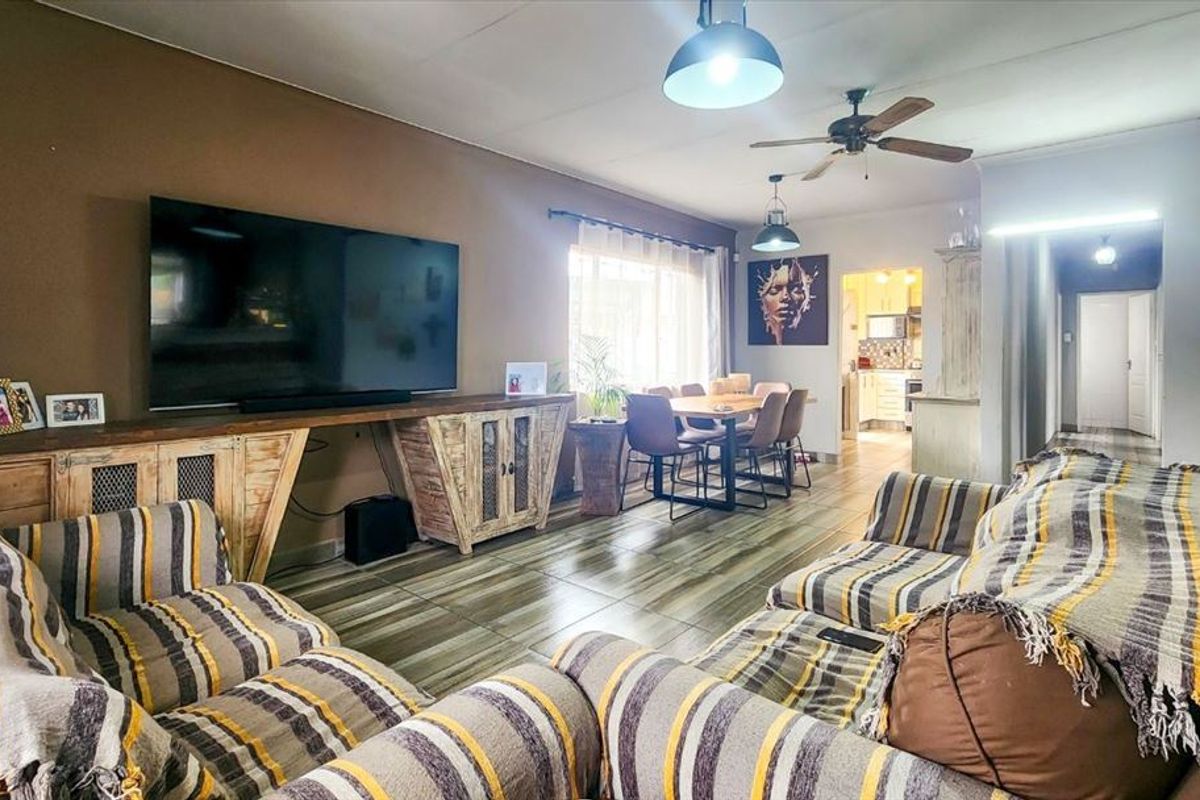 Open-plan living and dining area featuring tiled flooring, ceiling fan, and pendant lighting, with a seamless flow into the adjacent kitchen space.