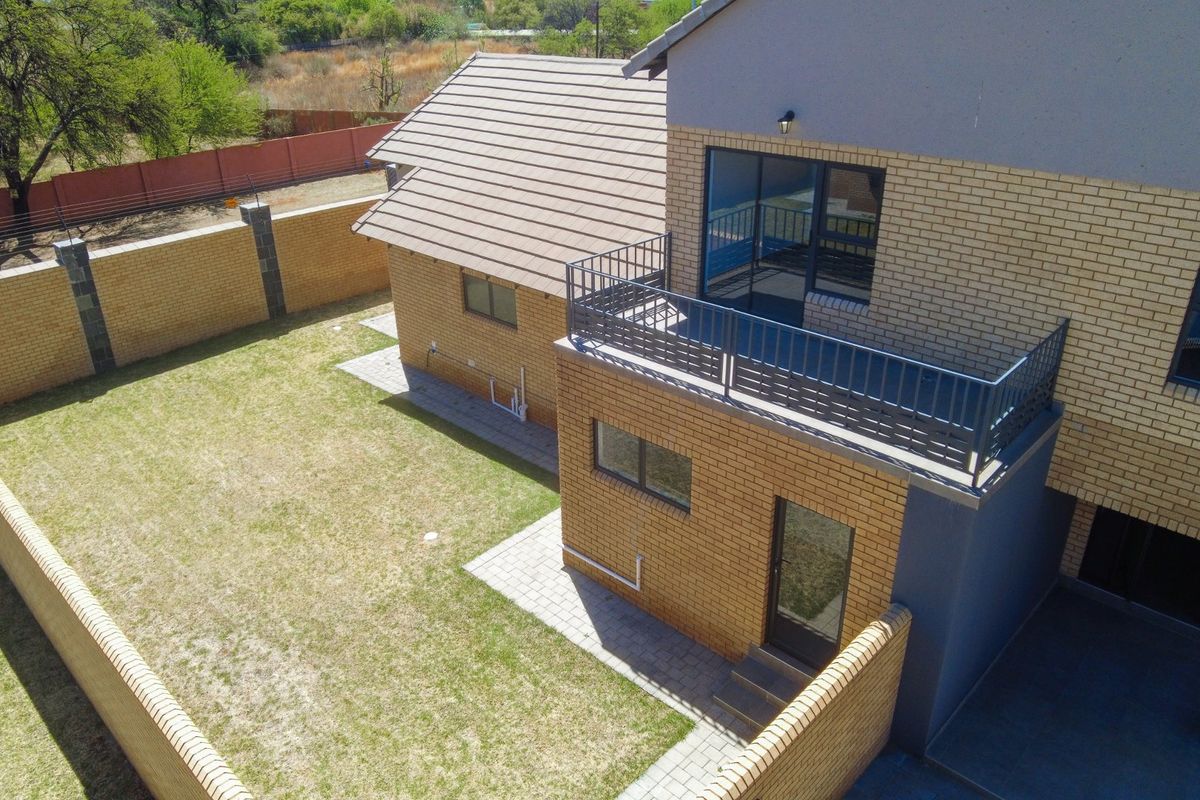 Aerial view of the townhouse rear exterior, featuring a private garden, paved walkway, and an elevated balcony with metal railings.