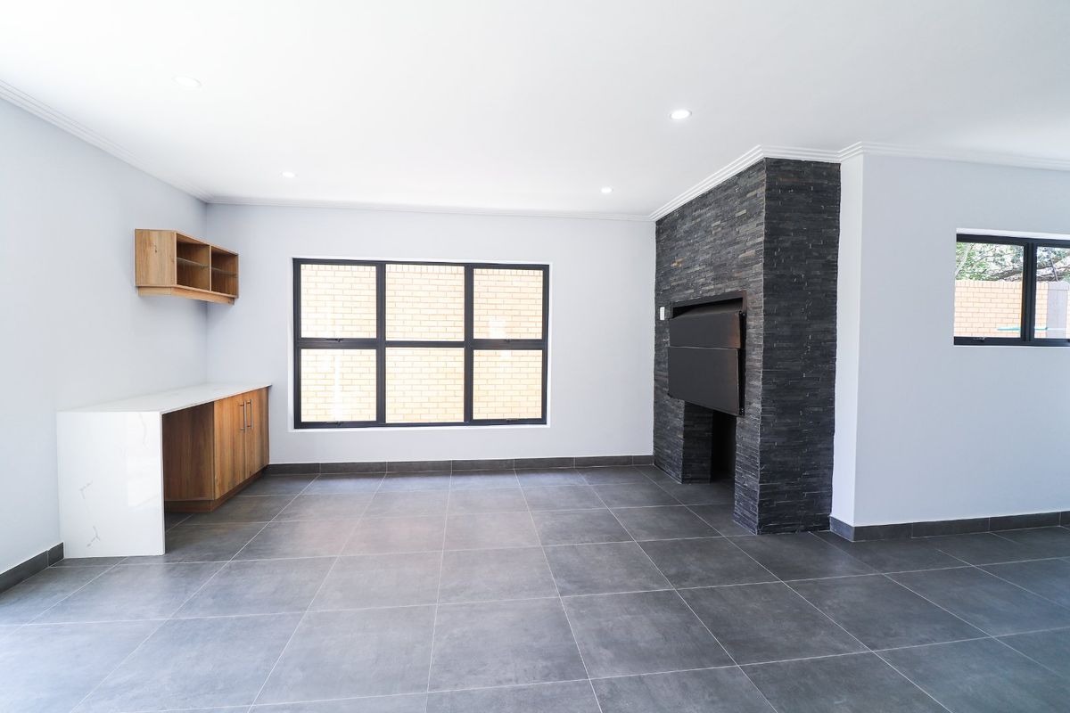 Spacious living area featuring large format floor tiles, a built-in stone fireplace, and custom cabinetry with a stone countertop.