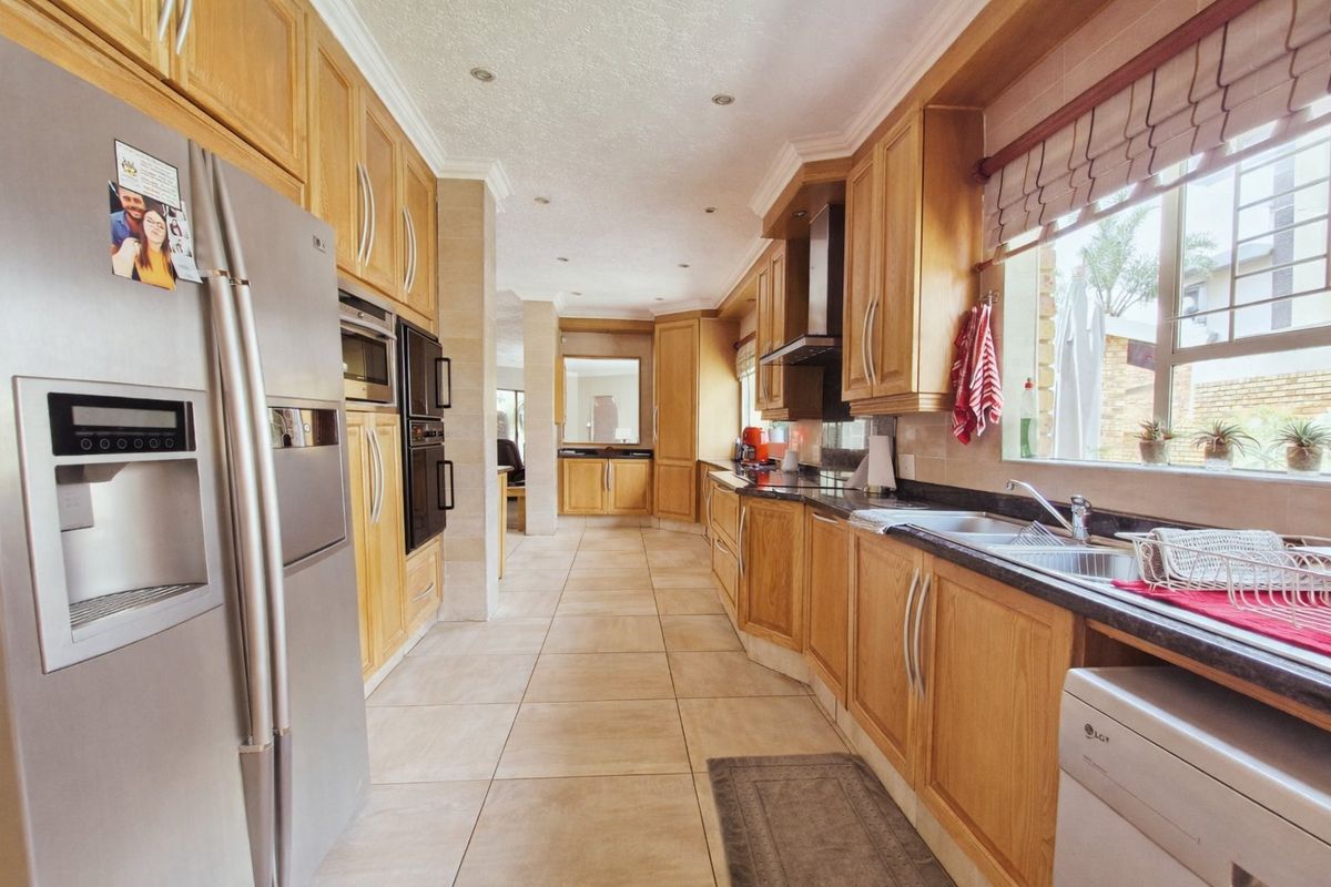 A spacious kitchen featuring extensive wooden cabinetry, granite countertops, integrated appliances, and tiled flooring, offering a functional layout with ample storage space.