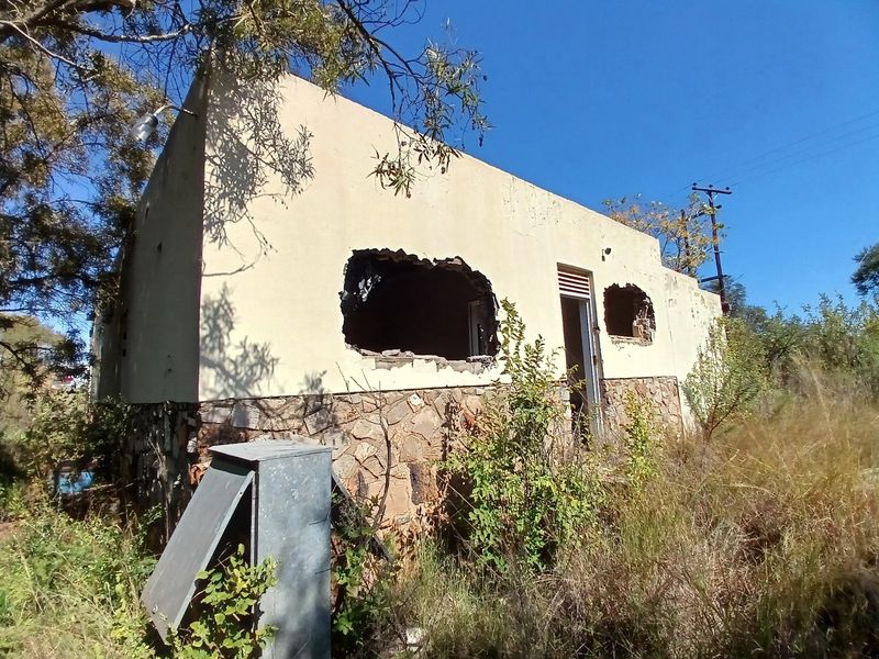 A severely dilapidated farm building structure featuring stone cladding and significant structural damage to the exterior walls.