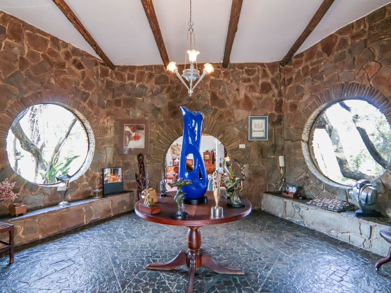 A unique entrance hall featuring rustic stone walls, exposed timber ceiling beams, circular windows with built-in stone benches, and elegant stone flooring.
