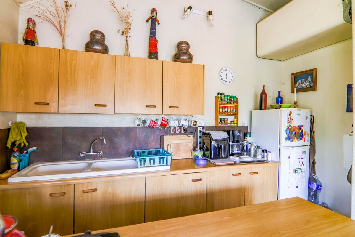 A functional kitchen featuring light wood-tone cabinetry, a double basin sink with a tiled splashback, and ample counter space for food preparation.