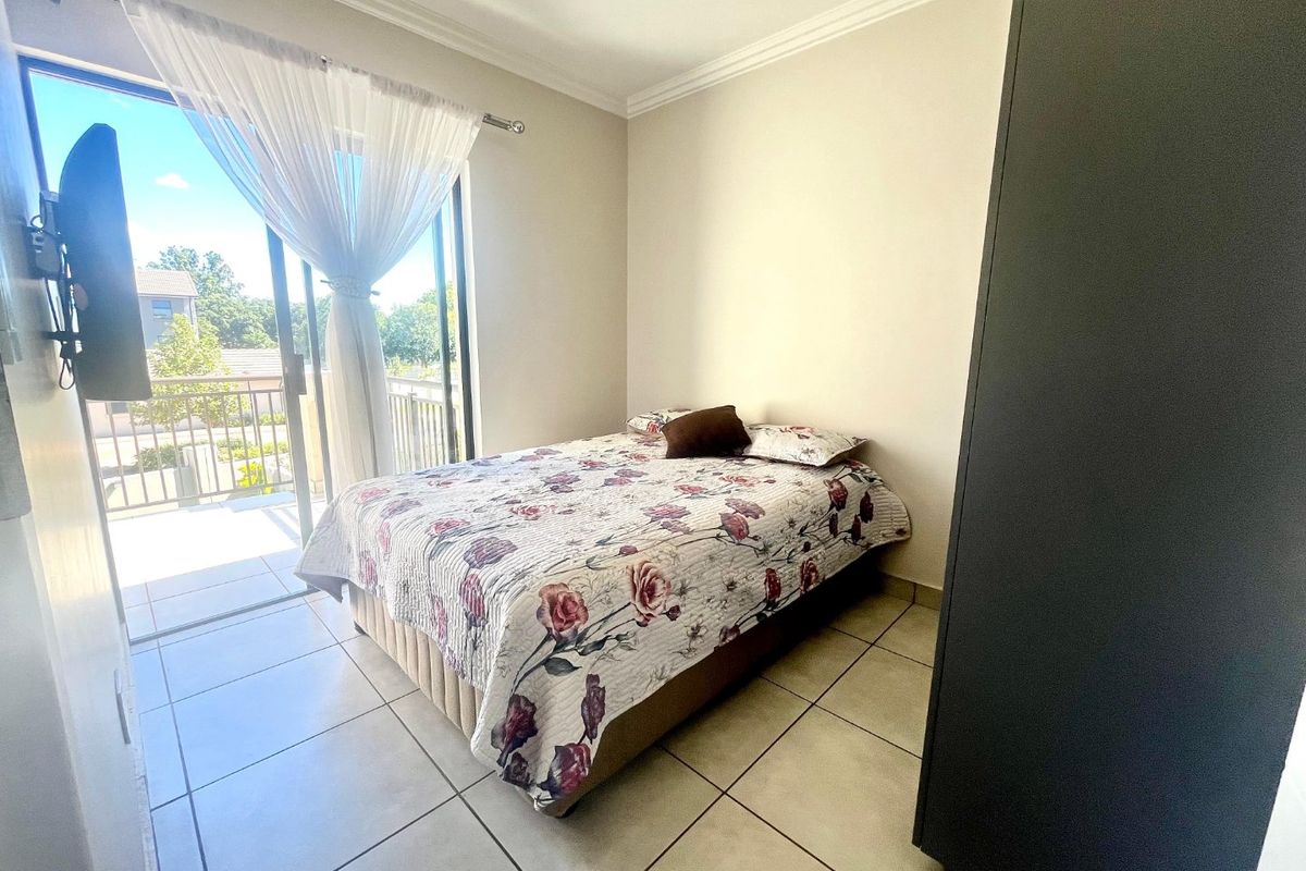 A bedroom featuring tiled flooring, crown molding, and a sliding glass door providing direct access to a private balcony.