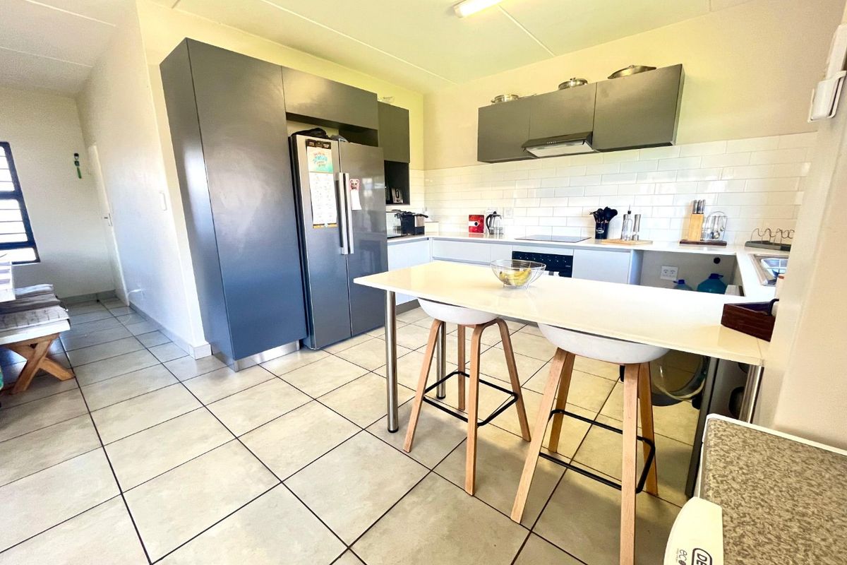 Modern kitchen featuring dark grey cabinetry, white subway tile backsplash, ceramic floor tiles, and a functional breakfast bar island.