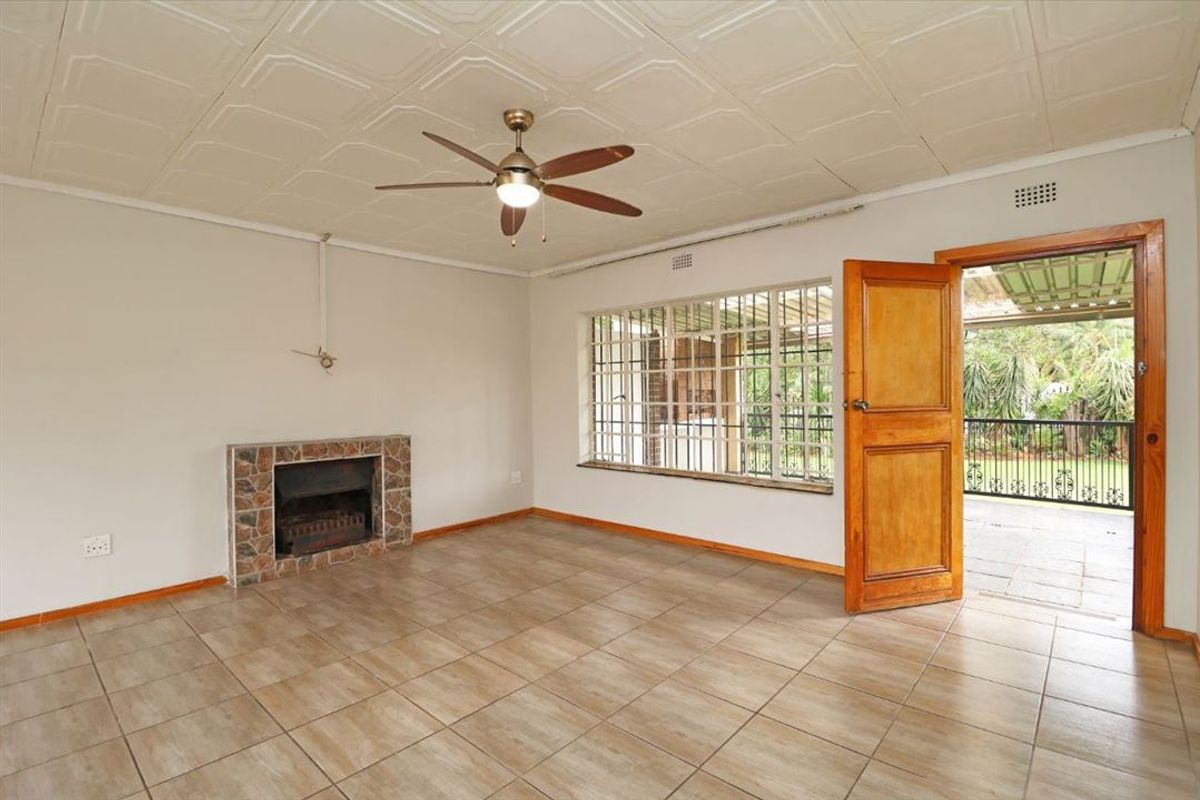 Spacious living room featuring tiled flooring, a stone-surround fireplace, ceiling fan, and direct access to an outdoor patio area.